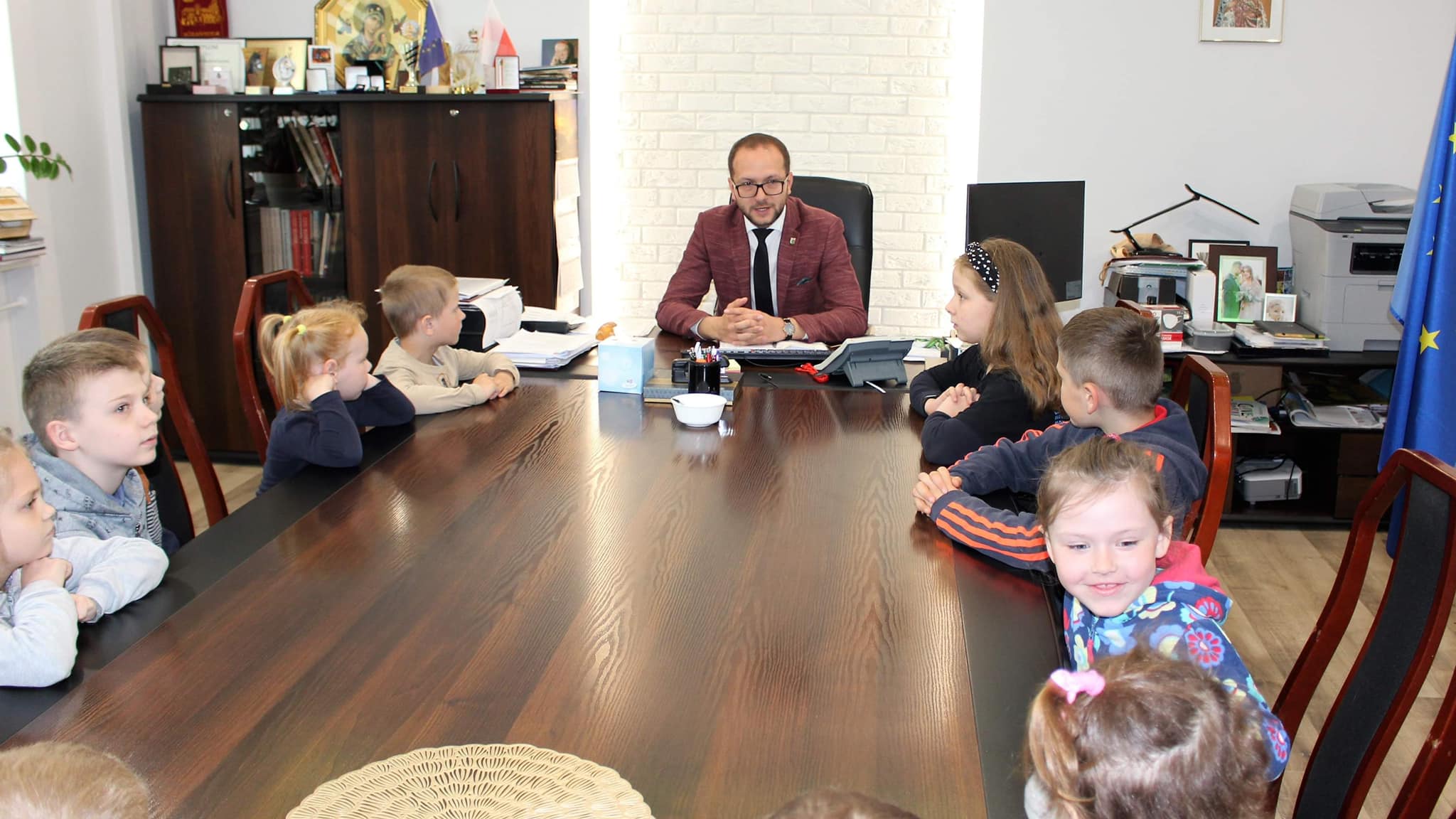 burmistrz w gabinecie z uczniami siedzi przy stole